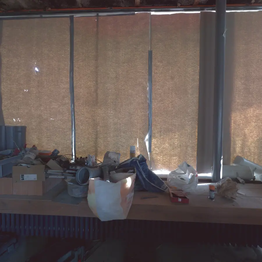 An ordinary site photo of a cluttered workbench in front of insulated windows.